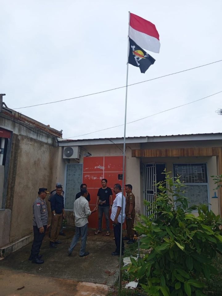 Polisi dibantu warga menurunkan bendera bergambar tokoh anime bajak laut One Piece yang berkibar di Perumahan Cipta Village, Batam, Minggu. Bendera ini diturunkan untuk menghindari kesalahpahaman di masyarakat menjelang peringatan HUT Kemerdekaan RI. Foto: Polsek Sekupang